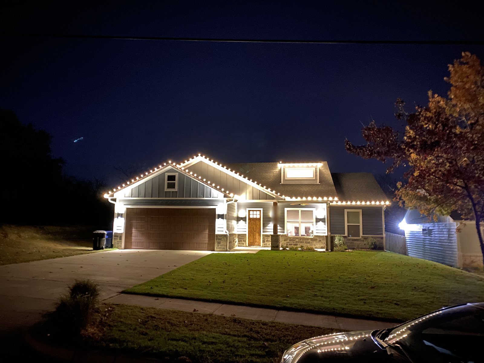 A craftsman-style home outlined in warm white C9 lights along every roofline, gable, and dormer